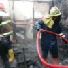 Dua orang petugas pemadam kebakaran berjibaku memadamkan kobaran api